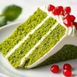 Ciasto leśny mech przepis siostry Anastazji na talerzu z widoczną zieloną warstwą ciasta, białym kremem i pestkami granatu na wierzchu