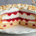 Ciasto malinowa chmurka siostry Anastazji na eleganckim talerzu z widocznymi warstwami: kruchym spodem, galaretką z malinami, kremem i bezą