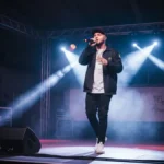 Quebonafide - polski raper w czarnych ubraniach na scenie während koncertu hip-hopowego